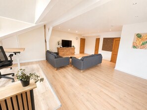 A spacious living area with a sofa set, a TV, and a wooden cabinet.