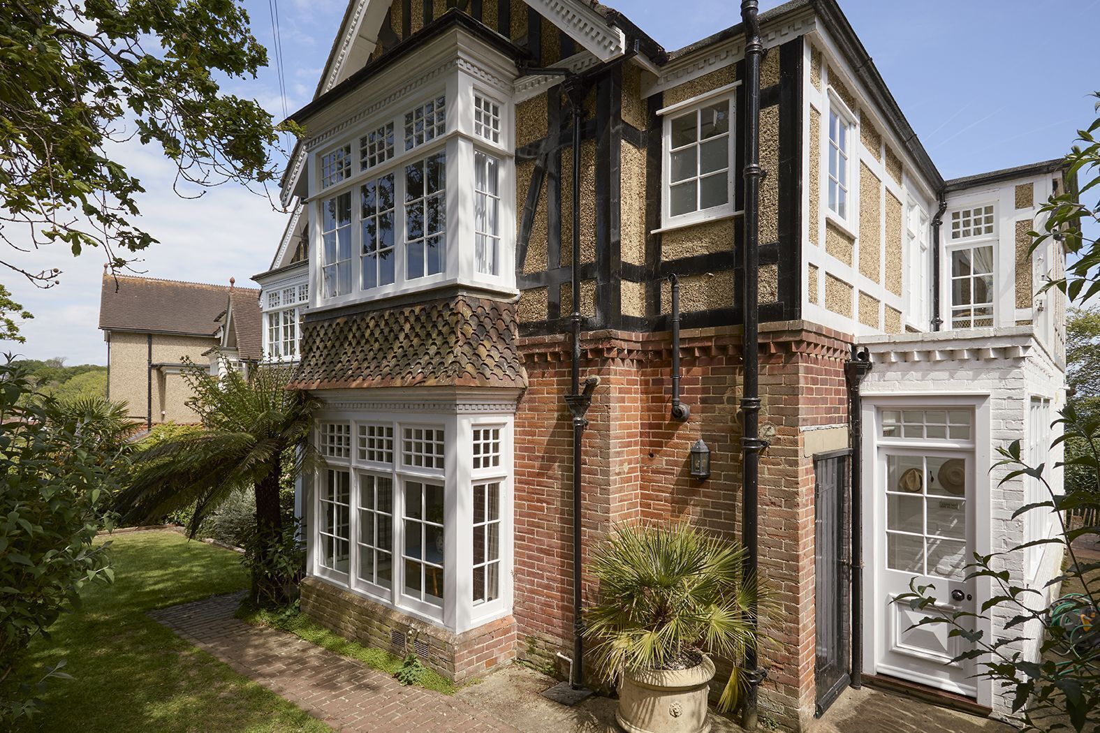 A two-story house with a bay window, a conservatory, and a brick facade.
