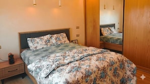 A bedroom with a large bed, wooden wardrobe, and a mirror. - Résidence Luxueuse, 2 Piscines Escapade Familiale à 2 pas Plages Harhoura Rabat (Harhoura)