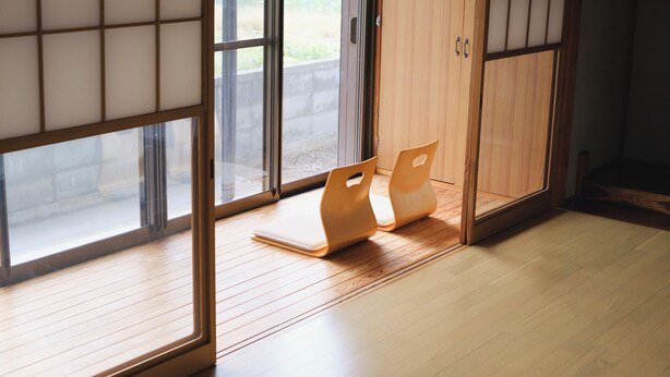 Una habitación con puertas correderas, piso de madera y vistas a través de las ventanas.