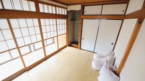 Una habitación japonesa tradicional con suelo de tatami, puertas correderas y techo con vigas de madera.