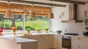 Una cocina moderna con una isla grande, armarios blancos, horno empotrado y ventana con vistas a un jardín.