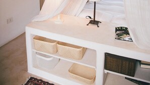 Un dormitorio con cama con dosel, una mesita de noche con lámpara y cestas de almacenamiento.