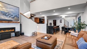 Un salon moderne avec une cheminée, un grand téléviseur et un coin salon confortable.