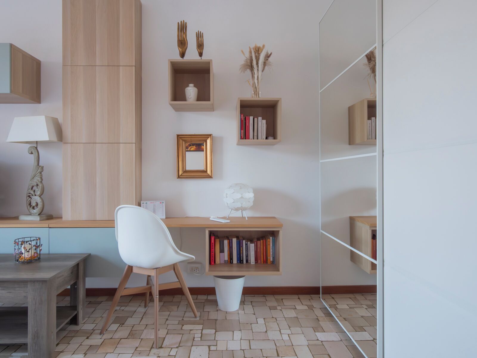 Una stanza moderna e ben organizzata con una scrivania in legno, una sedia bianca e scaffali.