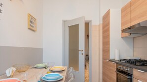 Eine moderne Küche mit Essbereich, ausgestattet mit einem Herd, Backofen und einem Esstisch, der mit Tellern und Gläsern gedeckt ist.