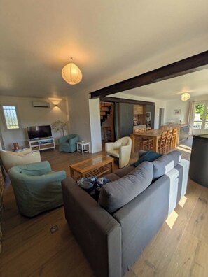 A modern living room with a sofa, a television, and a dining area with a table and chairs. - Villa Papillon (Monteux)