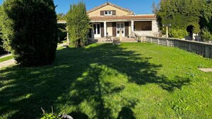 Ein zweistöckiges Haus mit Ziegeldach, einer Veranda und einem gepflegten Rasen.