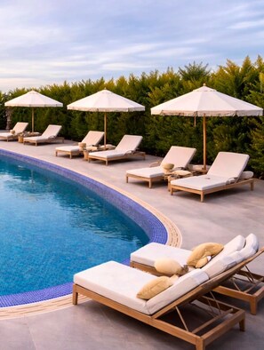 Un área junto a la piscina con sillas de descanso y sombrillas.