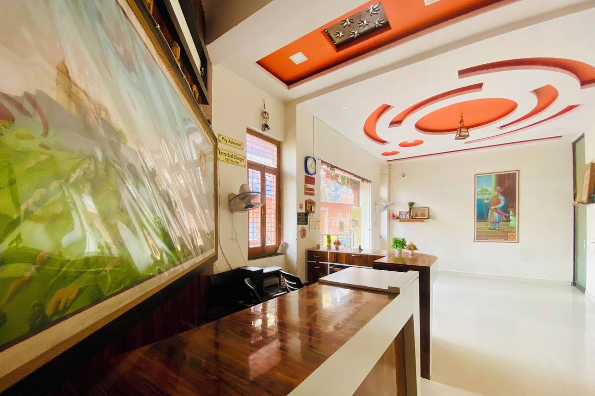 Un espace d’accueil d’hôtel avec un comptoir en bois, un grand tableau encadré et un plafond au design original.
