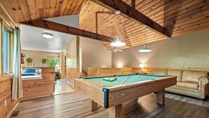 Ein Holzinterieur mit Billardtisch, einer Couch und einem Deckenventilator.