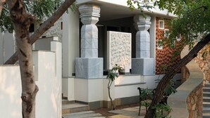 A modern building with stone columns, a stone staircase, and a small tree in the foreground. - Vihara Udaipur (Udaipur)
