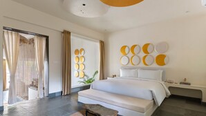 A modern bedroom with a large bed, a small bench, and a wall with circular decor. - Vihara Udaipur (Udaipur)