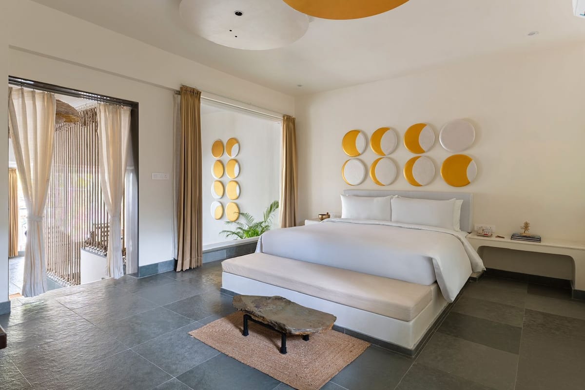 Un dormitorio moderno con una cama grande, un pequeño banco y una pared decorada con motivos circulares.