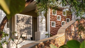 A modern building with a stone facade, a curved stone pathway, and a large window. - Vihara Udaipur (Udaipur)