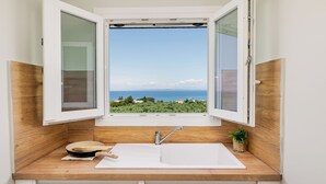 A kitchen with a large window, wooden countertop, and a white sink. - Restia tower apartments (Zakynthos)