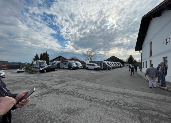 A parking lot with RVs and cars, a building with 'Polo' signage, and a cloudy sky. - Hotel Zur Post (Buechlberg)
