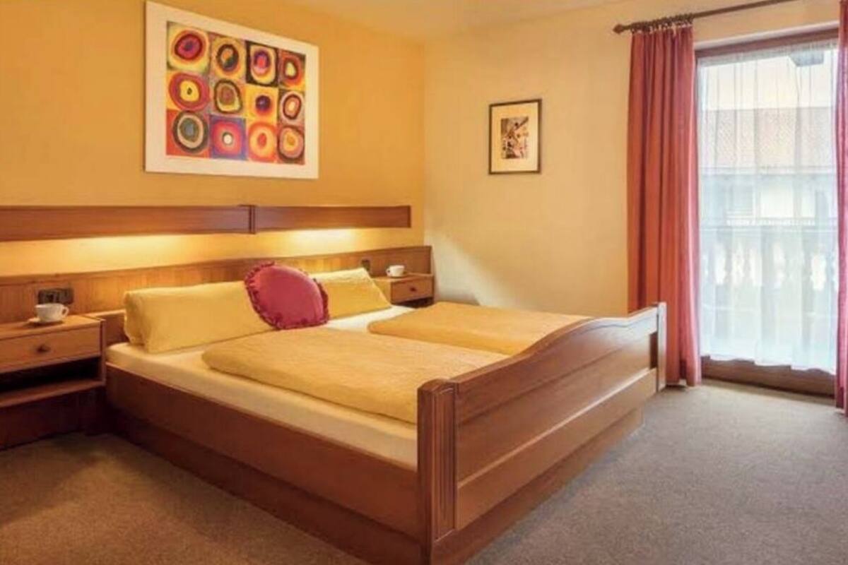 A double bed with a wooden frame, a headboard, and a bedside table with a lamp.