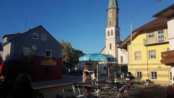 A town square with a church steeple, outdoor seating, and bicycles.
