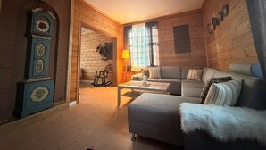 A cozy log cabin interior with a sofa, a rocking chair, and a wooden wall clock. - Cabane à Oppdal (Trøndelag)