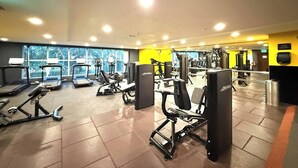 Ett gym med löpband, styrketräningsmaskiner och en vägg med speglar.