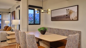 Un comedor moderno con una mesa redonda, sillas estampadas, una planta en maceta y un cuadro con un caballo en la pared.