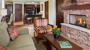 Una sala de estar acogedora con chimenea, un sofá, una mesita de centro y una cocina al fondo.