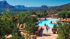 Un resort con piscina, sillones de descanso y montañas al fondo.