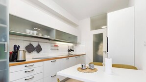 A modern kitchen with white cabinets, a stainless steel kettle, and a table with a white mug and a cup. - Greco Heritage Suite in Milan (Milan)