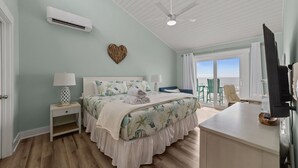 Une chambre à coucher avec un lit, des tables de chevet, une télévision et un balcon avec vue.