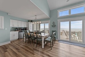 Una cocina amplia con comedor, ventanas grandes y vista al mar.