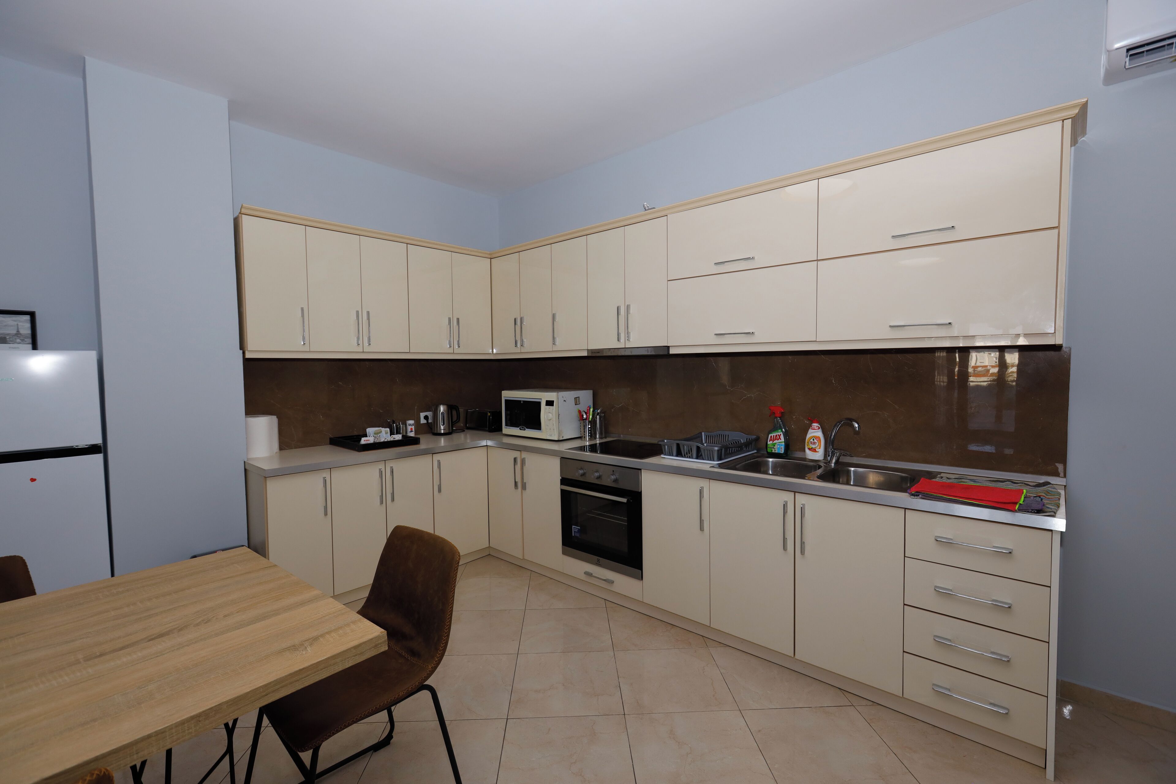 A compact kitchen with white cabinets, a microwave, an oven, and a sink. There is a dining table with chairs.