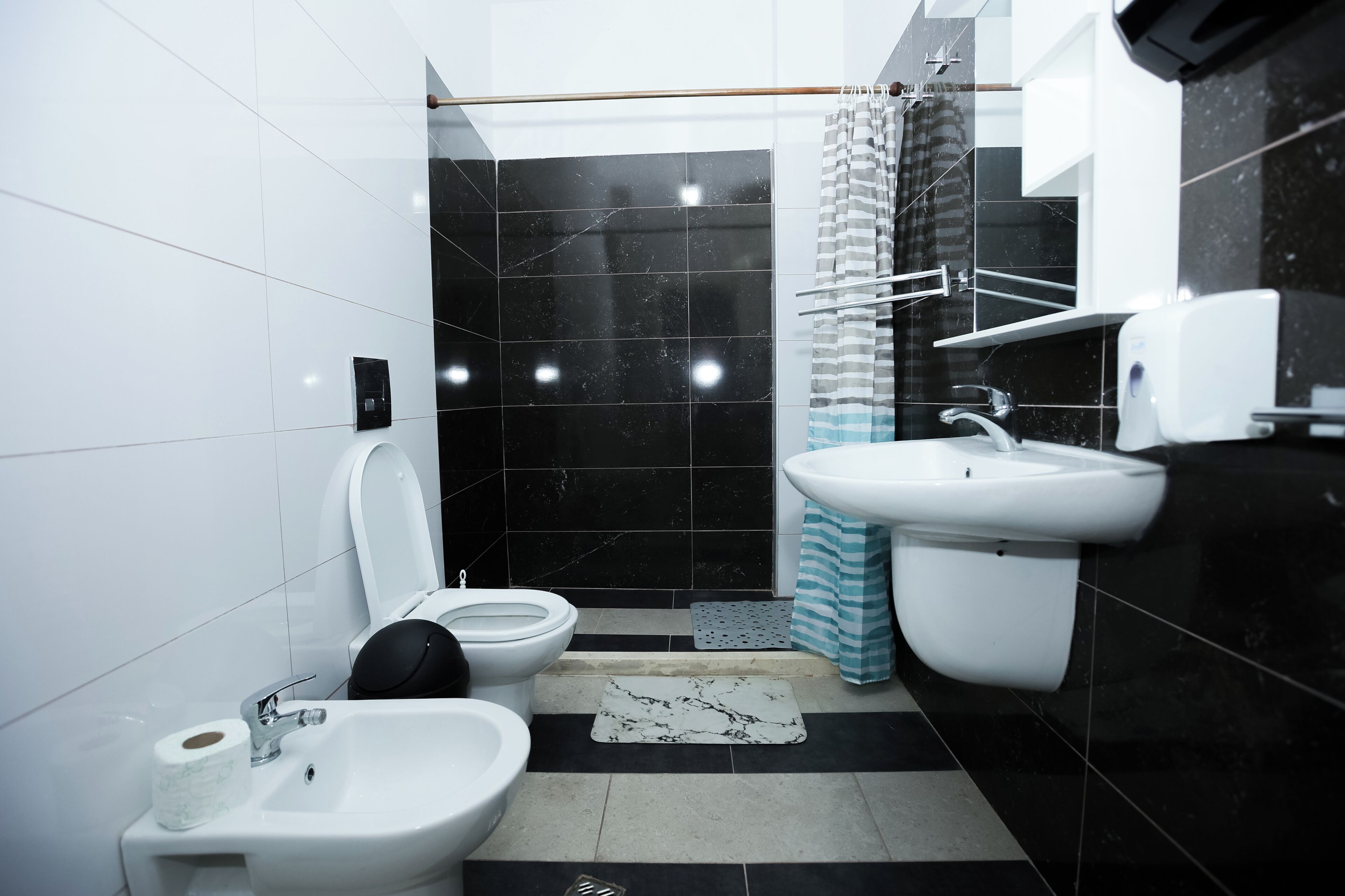 A modern bathroom with a toilet, bidet, sink, and shower.