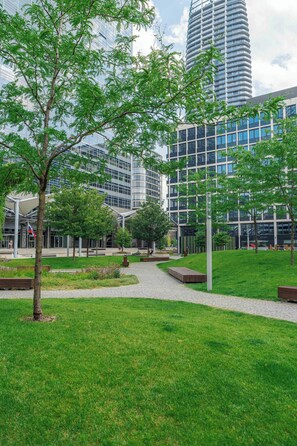 Ein moderner Stadtpark mit gepflastertem Weg, Bänken und Bäumen.