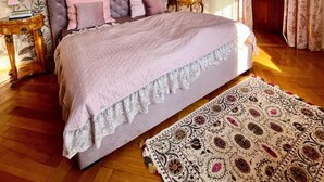 A bedroom with a bed, a nightstand, a lamp, a patterned rug, and a floral wallpaper. - Design apartment in the Sternkopf-Engel-Villa (Oederan)