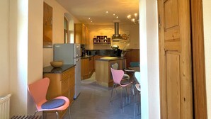 A modern kitchen with a central island, wooden cabinets, and a dining area with chairs. - Design apartment in the Sternkopf-Engel-Villa (Oederan)