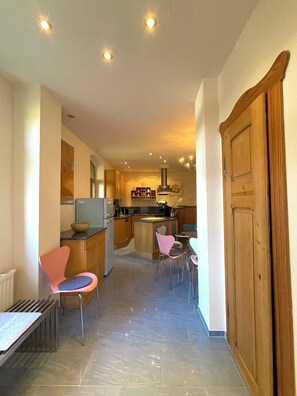 A modern kitchen with a central island, wooden cabinets, and a dining area with chairs.