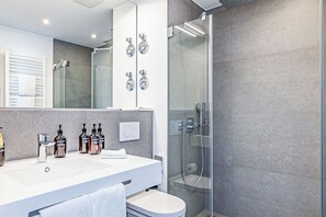 A modern bathroom with a glass-enclosed shower, a white sink, and a large mirror. - Atlantic Dependance Travemünde (Lübeck)