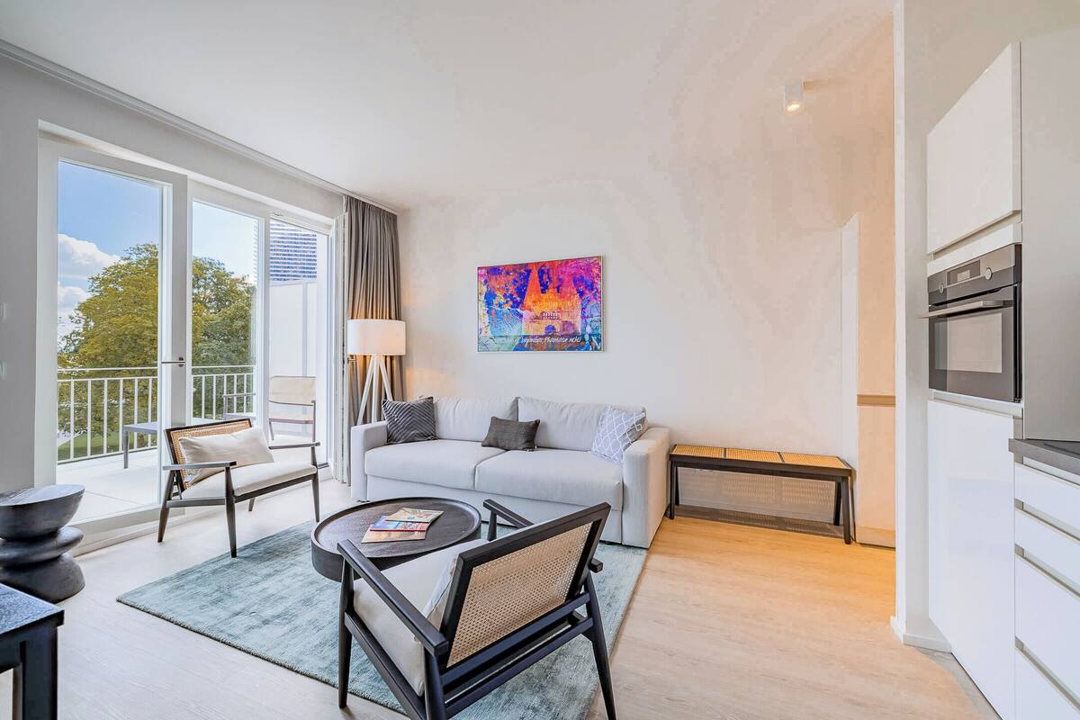 Ein modernes Wohnzimmer mit einer Couch, Sesseln, einem Couchtisch und einem Gemälde an der Wand.