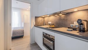 Een moderne keuken met witte kasten, een inbouwoven en een koffieapparaat.