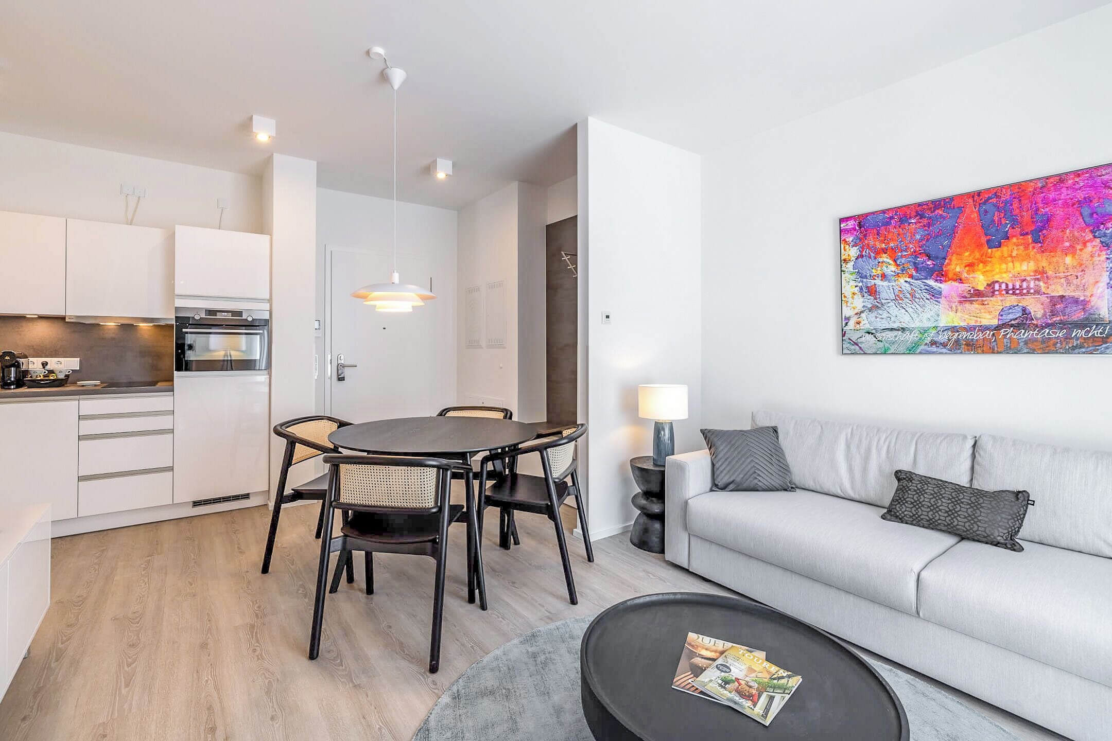 En moderne lejlighed med spiseplads, tekøkken og en stue med sofa og sofabord.