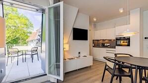Een modern appartement met balkon, een eethoek en een keuken.