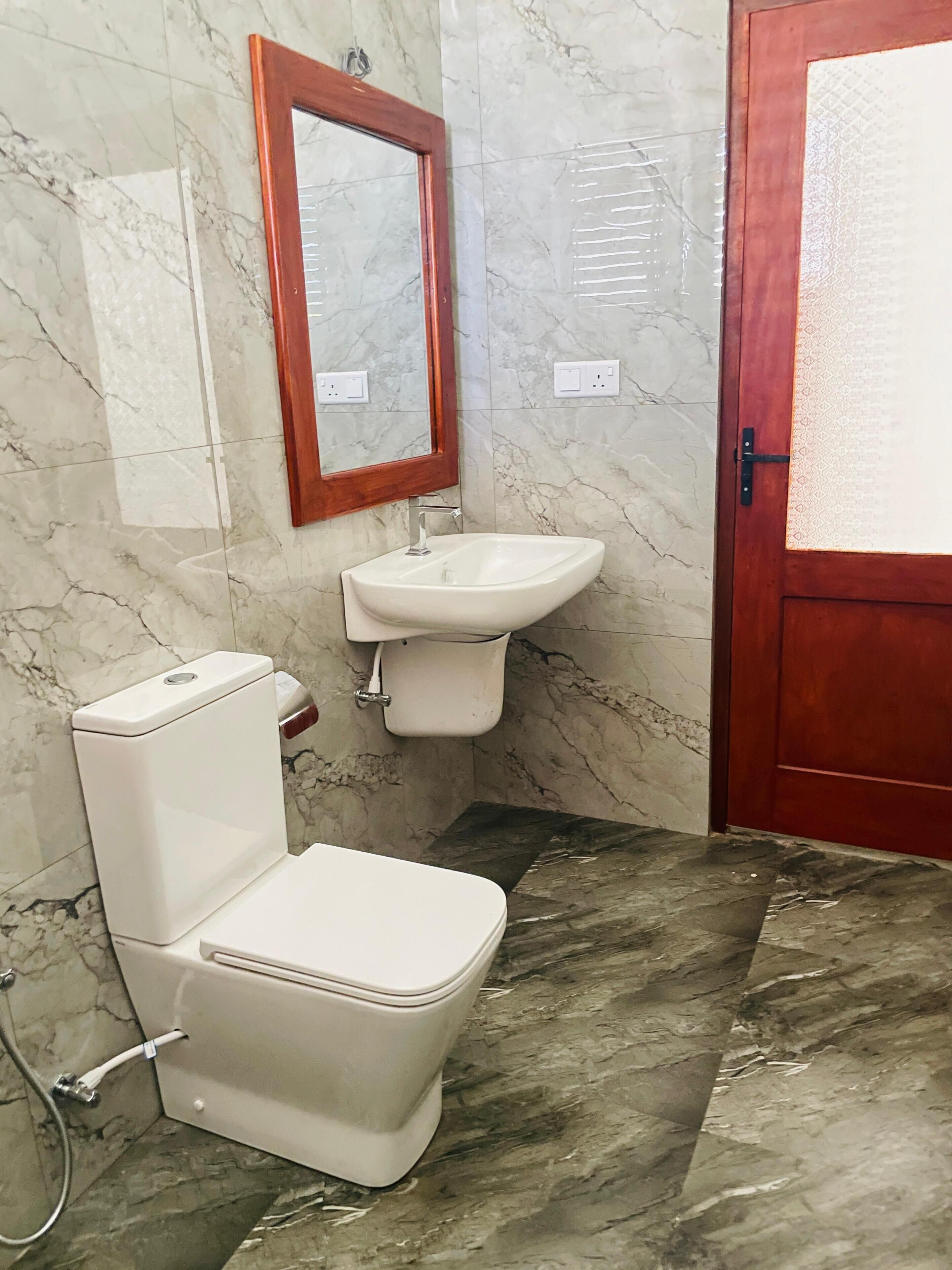 A bathroom with a toilet, sink, and mirror.