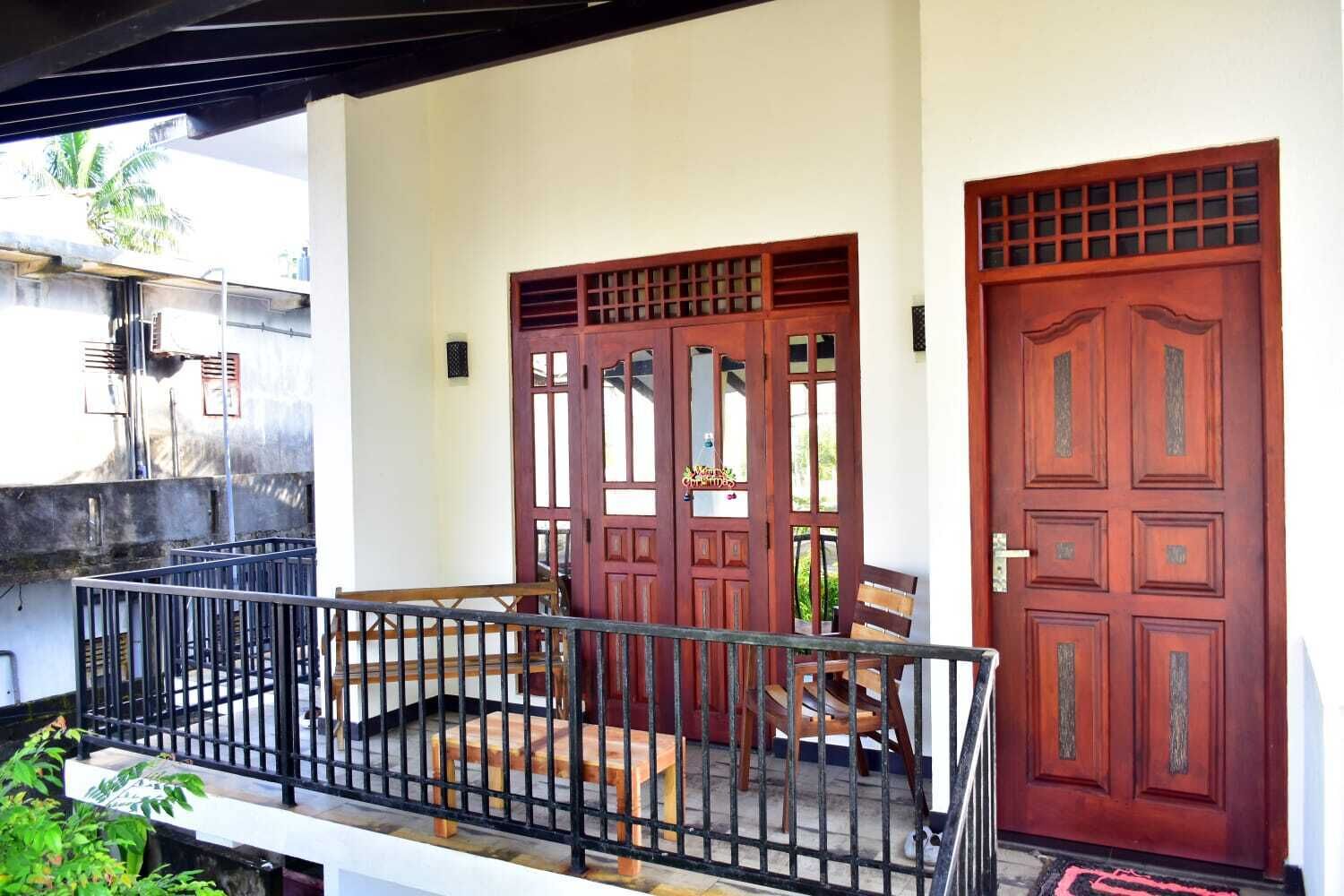 A balcony with a metal railing, two wooden doors with glass panels, and a bench.