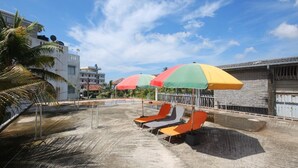 Ein Poolbereich auf dem Dach mit bunten Sonnenschirmen und Liegestühlen.