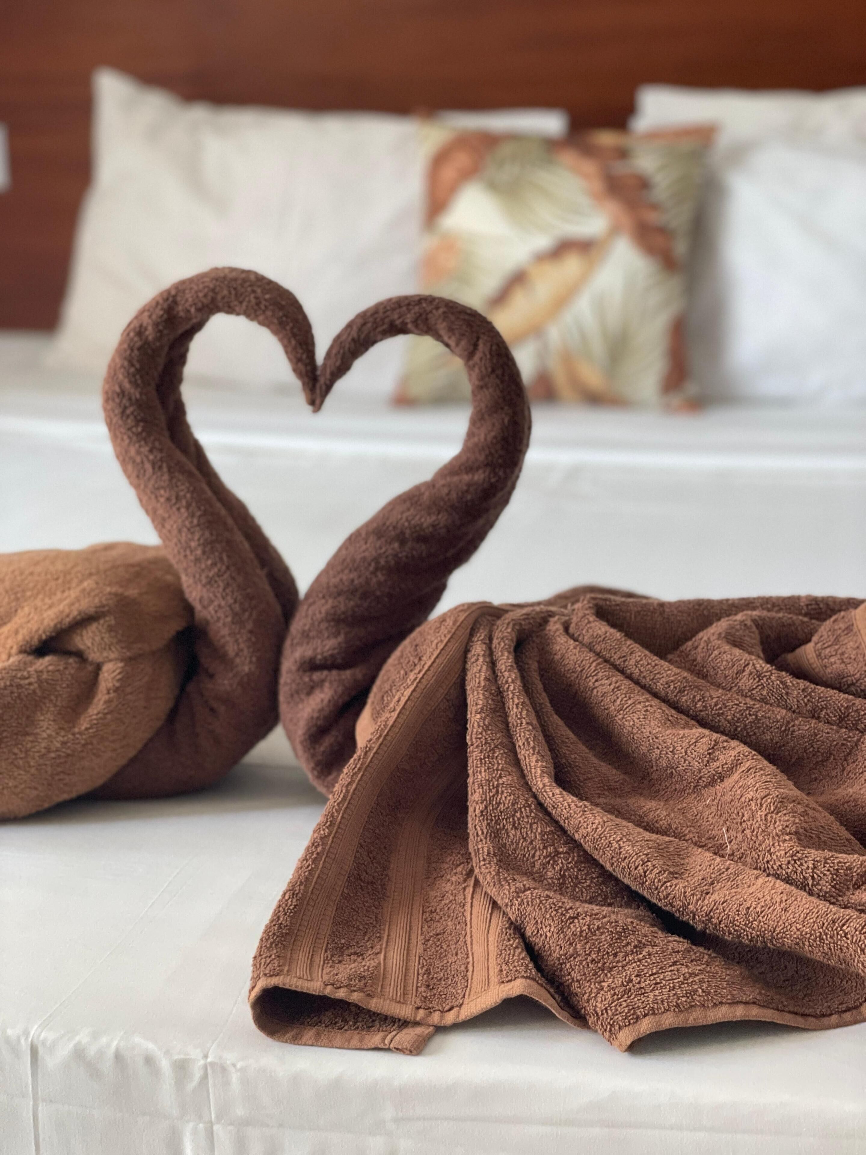 Ein Bett mit einem braunen Handtuch, das zu einem Schwan geformt ist.