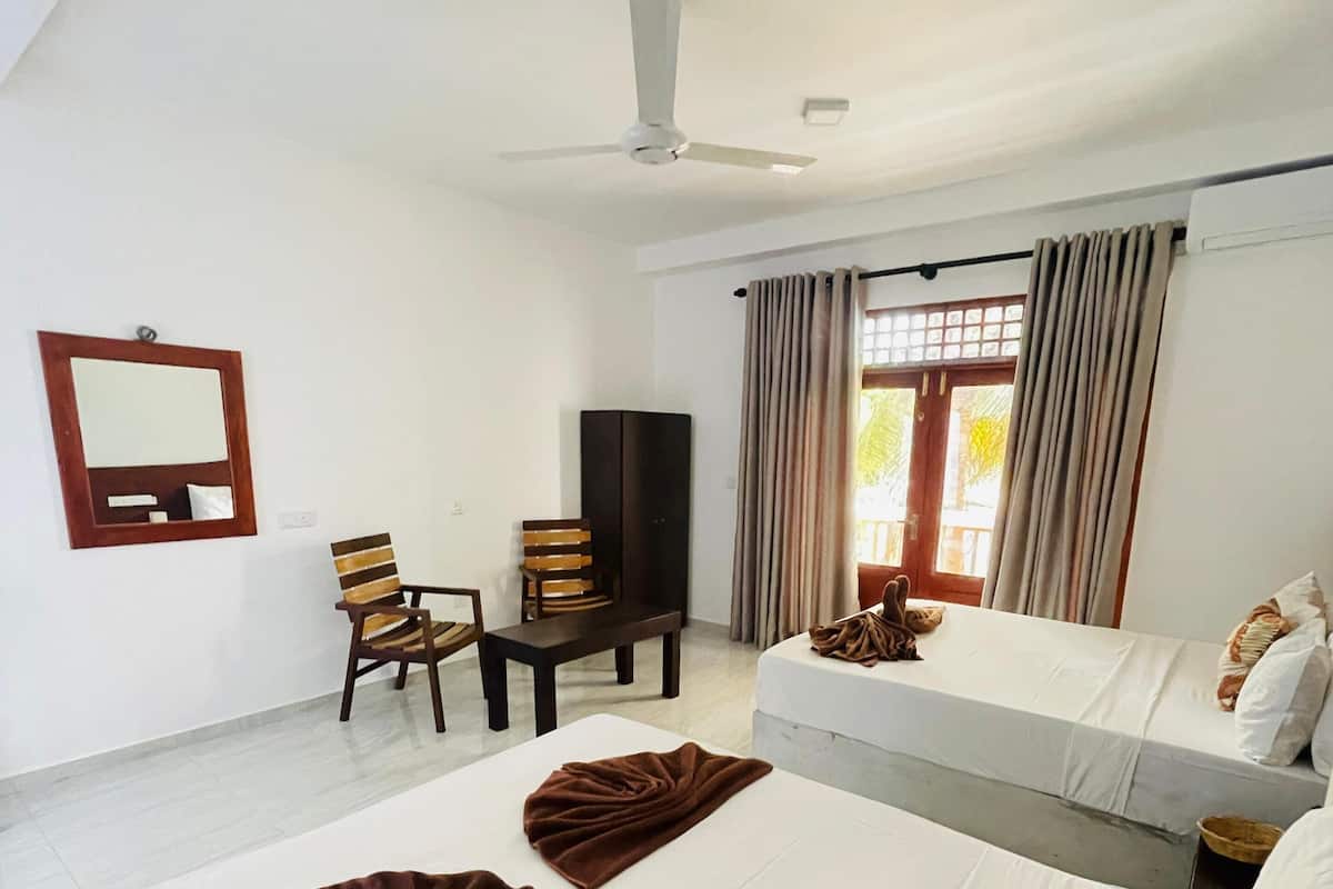 A hotel room with two beds, a desk, a chair, a television, and a window with curtains.