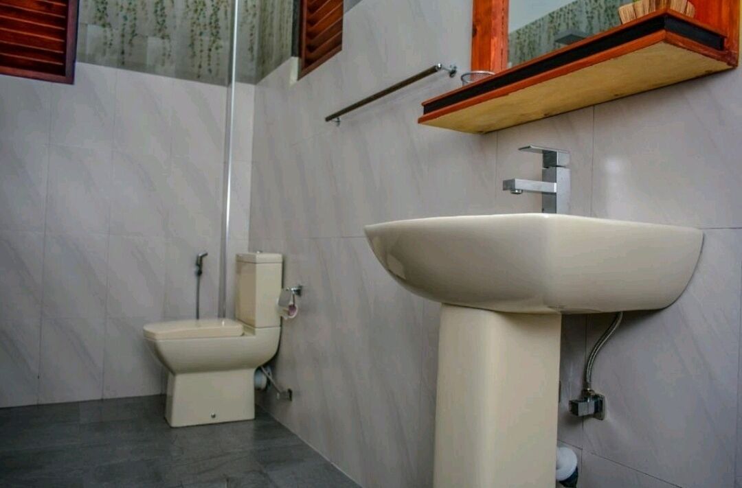 Un baño con inodoro, lavamanos y espejo.