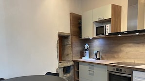 Une cuisine compacte dotée d’un plan de travail en bois, d’un four encastré et d’un four à micro-ondes.