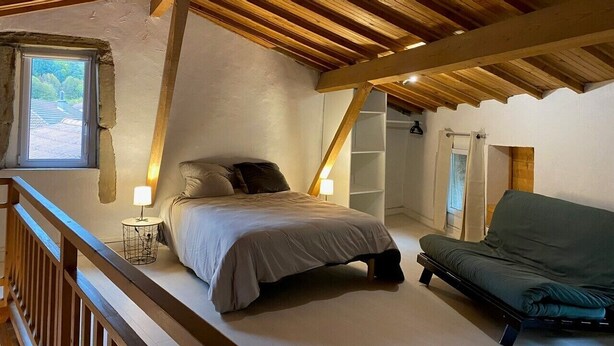 Ein Schlafzimmer mit einem Bett, einem Nachttisch, einem Sofa und einem Fenster.